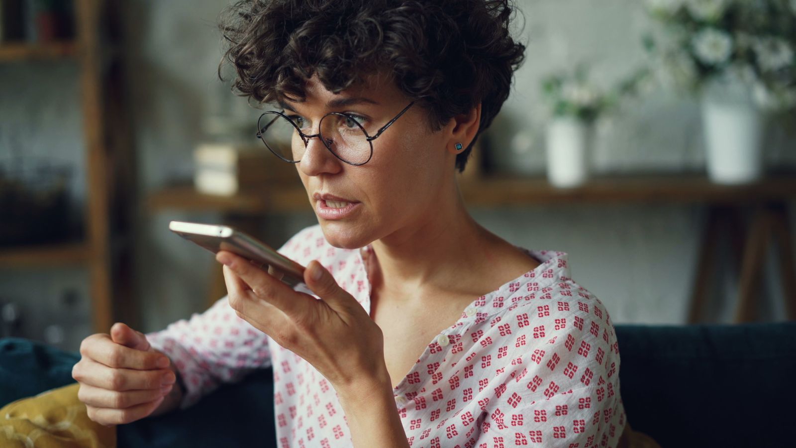 A woman recording a voice note on her smartphone at home